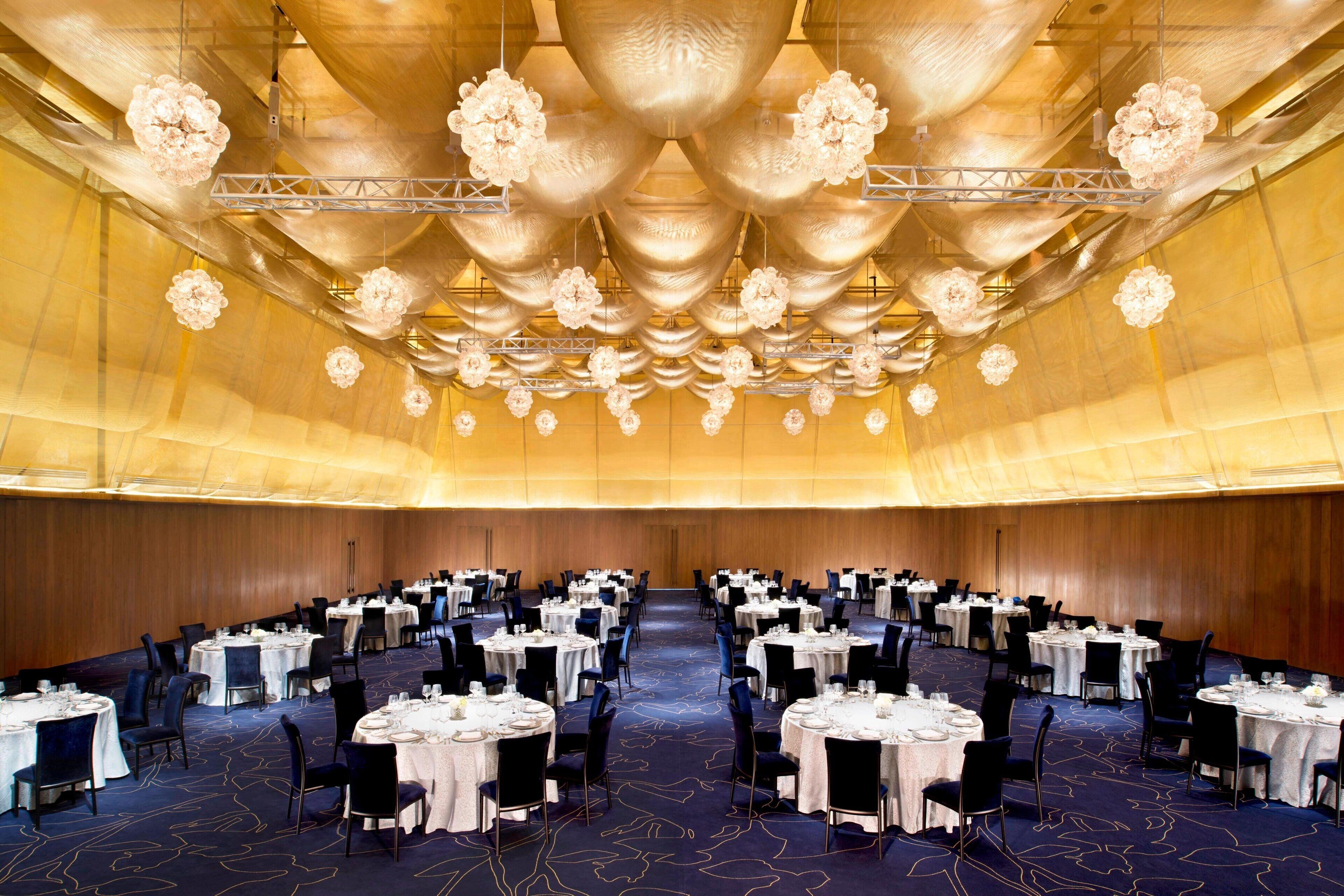 A banquet hall with round tables, chairs, and a decorative ceiling.