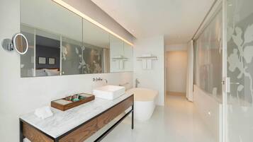 A modern bathroom with a large mirror, two sinks, a bathtub, and a shower.