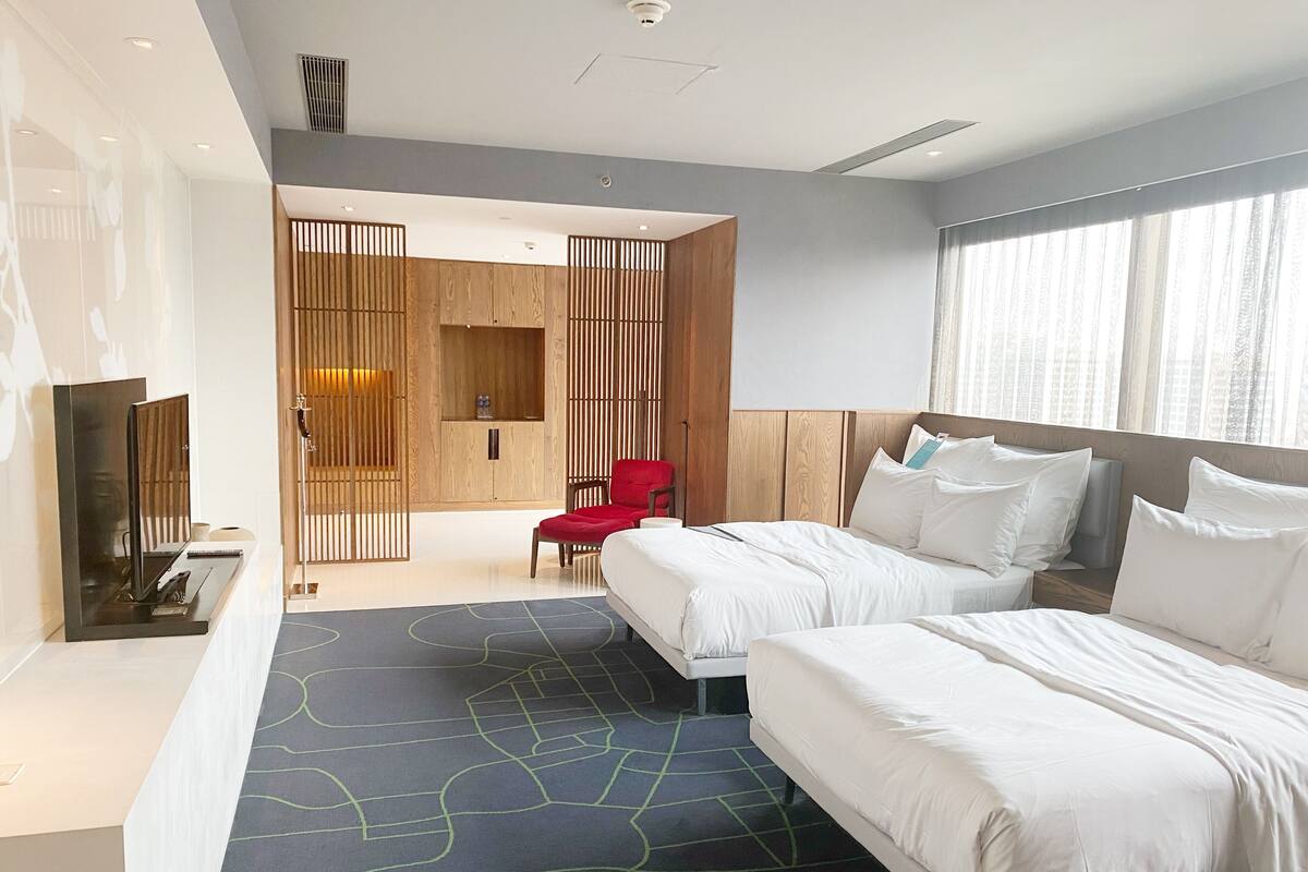 Een moderne hotelkamer met een groot bed, een bureau, een televisie en een rode fauteuil.