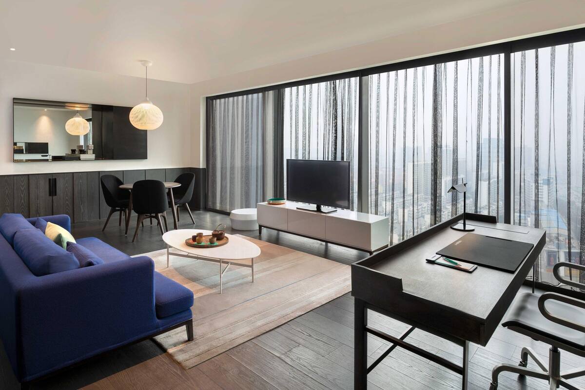 Een moderne woonkamer met een bank, salontafel, televisie en eethoek.