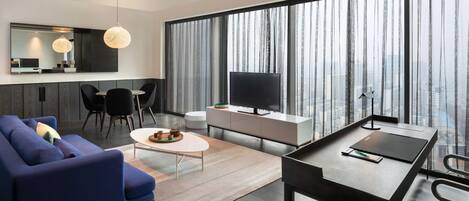 Uma sala de estar moderna com sofá, mesa de centro, televisão e área de jantar.