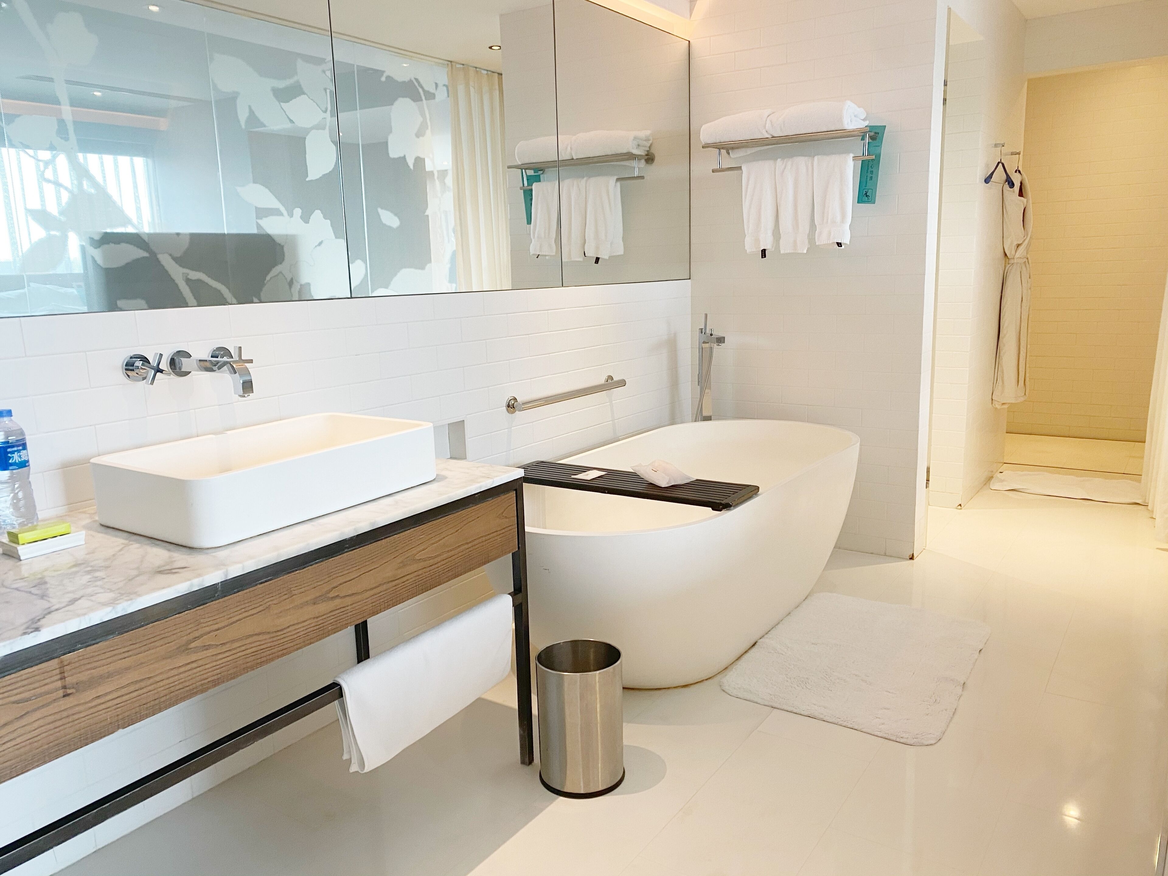 A modern bathroom with a white sink, a bathtub, and a mirror.