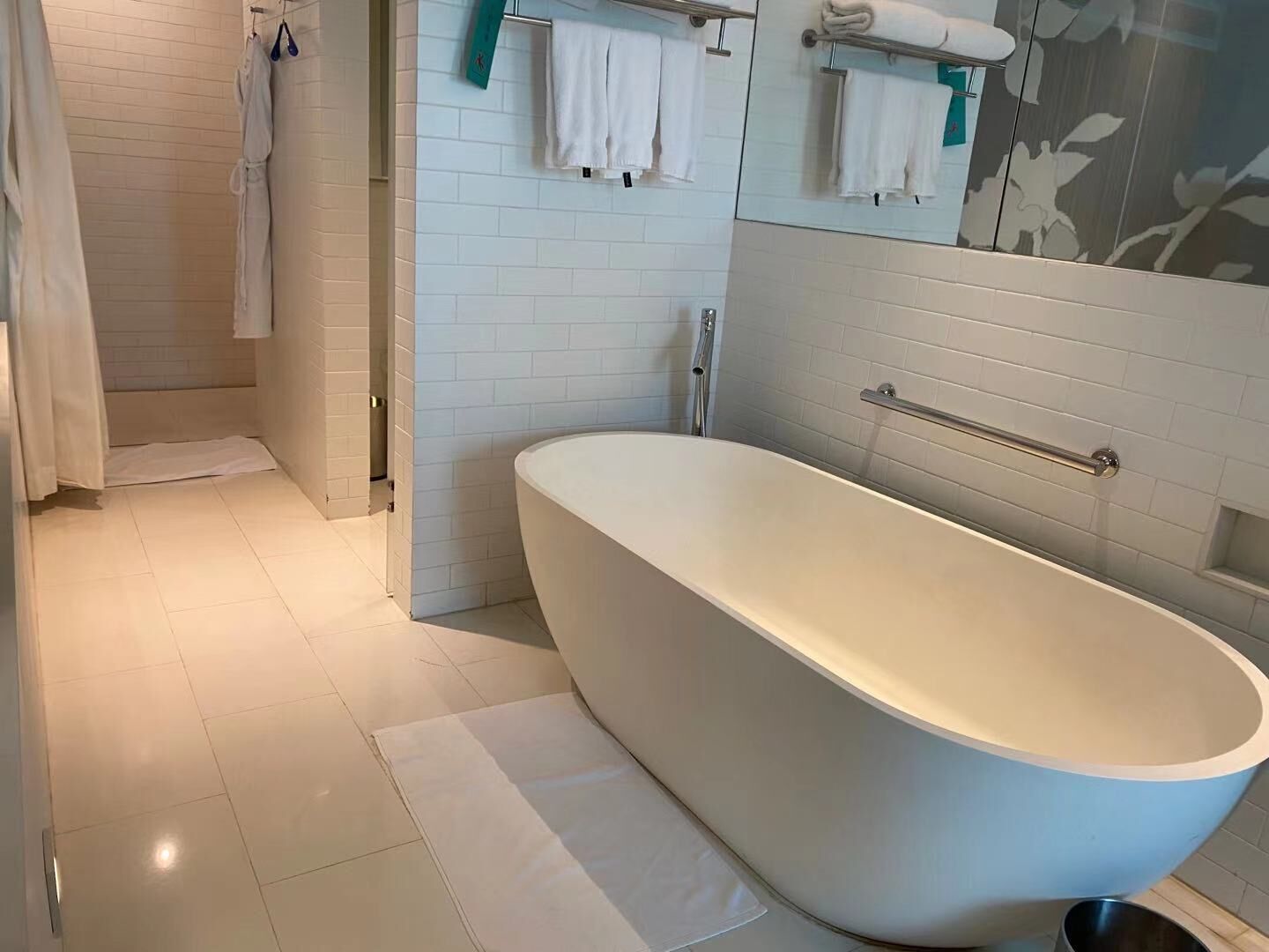 Un baño moderno con una bañera independiente, paredes de azulejos blancos y una zona de ducha.