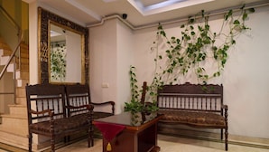 A room with two wooden benches, a small table with a red cloth, and a mirror with an ornate frame. - New City Hotel (Istanbul)