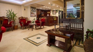 A lobby with red upholstered chairs, a reception desk, and a large mirror. - New City Hotel (Istanbul)