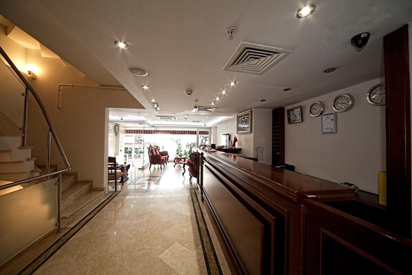 A hotel lobby with a reception desk, a staircase, and a view into the dining area.