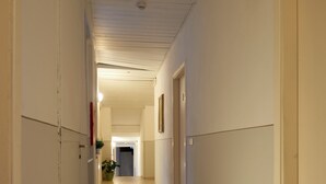 Un couloir doté d’un plancher en bois, de murs blancs et de portes de part et d’autre.