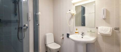 Une salle de bain avec une douche à parois de verre, des toilettes blanches, un lavabo et un miroir.