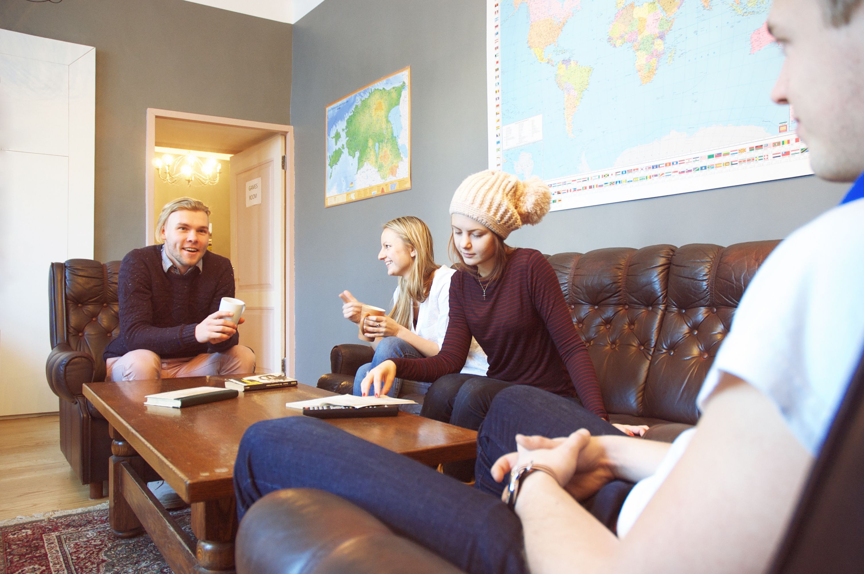A group of people sitting on a leather couch in a room with a world map on the wall.