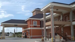 A multi-story building with a covered parking area, a staircase, and a clear sky.