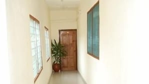 A narrow hallway with a tiled floor, wooden doors, and a potted plant.