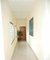 A narrow hallway with a tiled floor, wooden doors, and a potted plant.