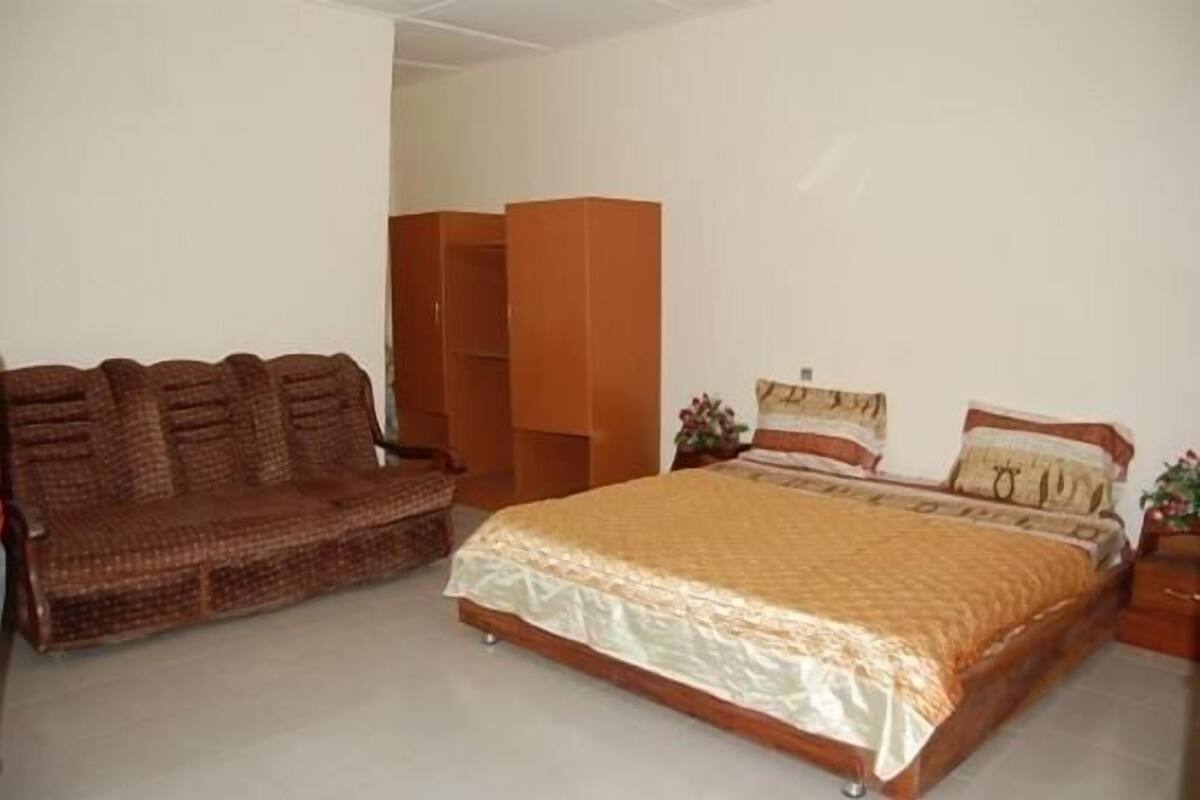 A bedroom with a bed, a sofa, and a wardrobe.