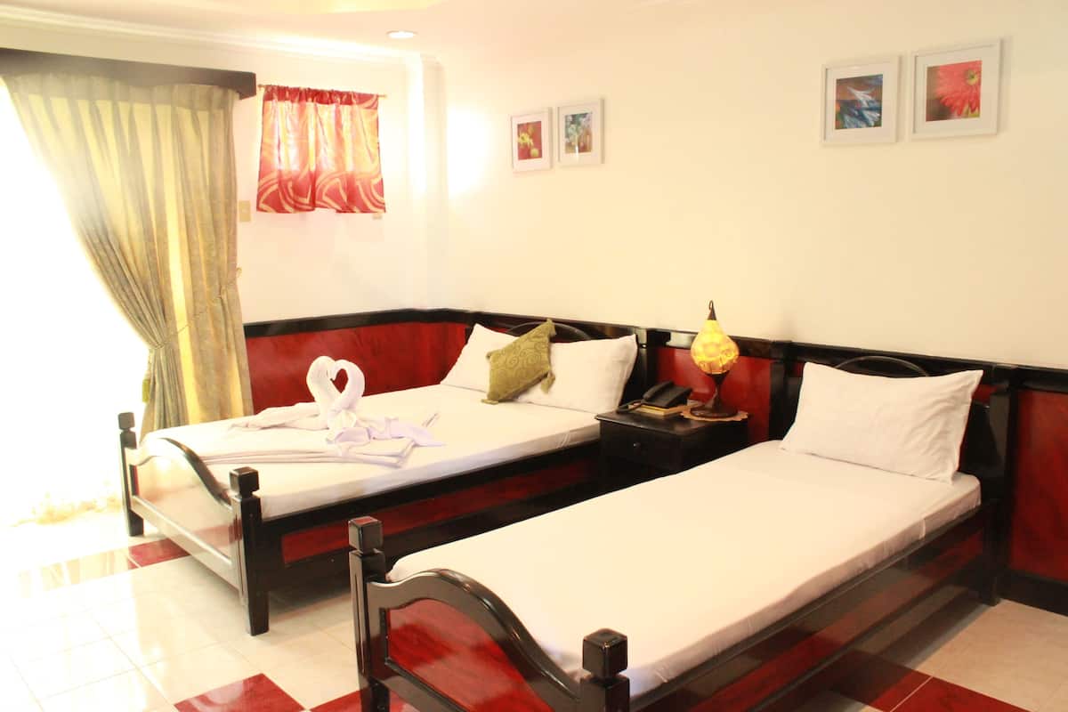 A hotel room with two single beds, a nightstand with a lamp, and a window with curtains.