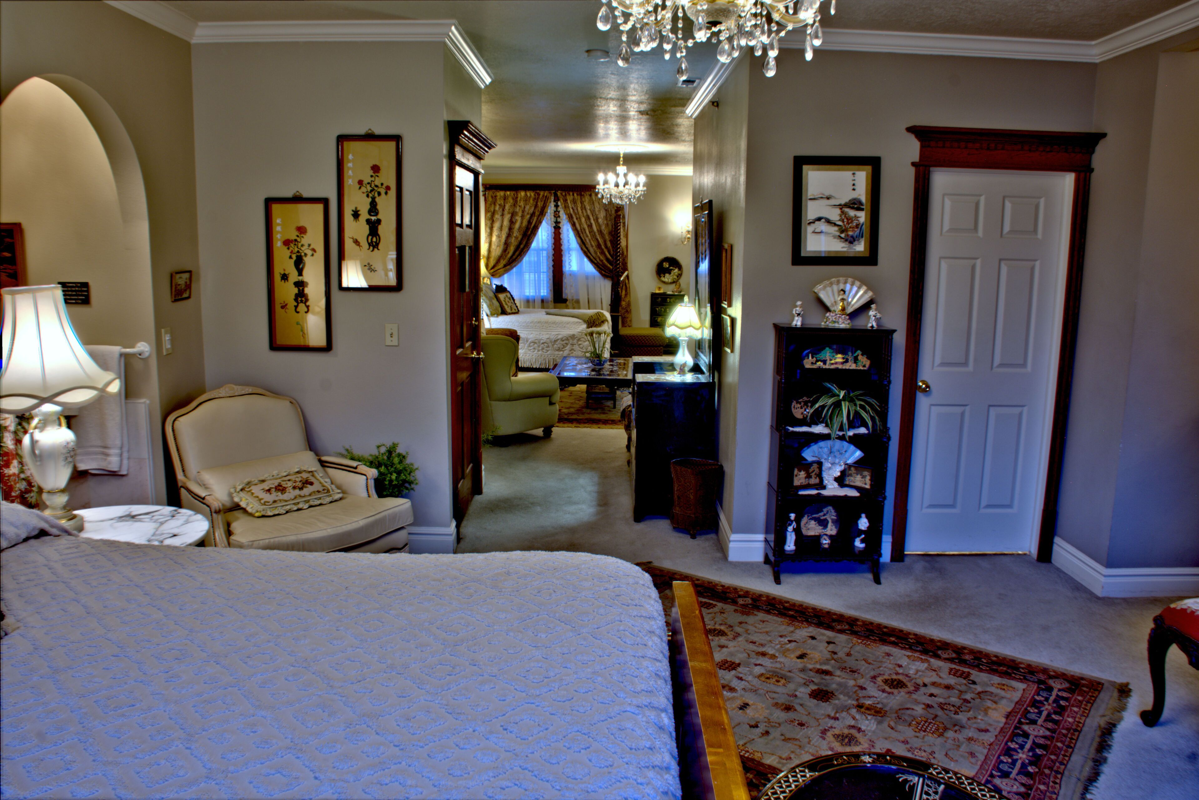 A bedroom with a large bed, a chair, a desk, and a bookshelf.