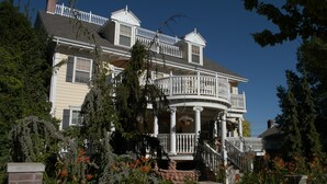 A large, two-story house with a balcony and a wrap-around porch. - Big Yellow Inn (Cedar City)