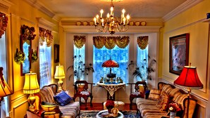 A formal living room with a chandelier, sofas, armchairs, and a coffee table. - Big Yellow Inn (Cedar City)