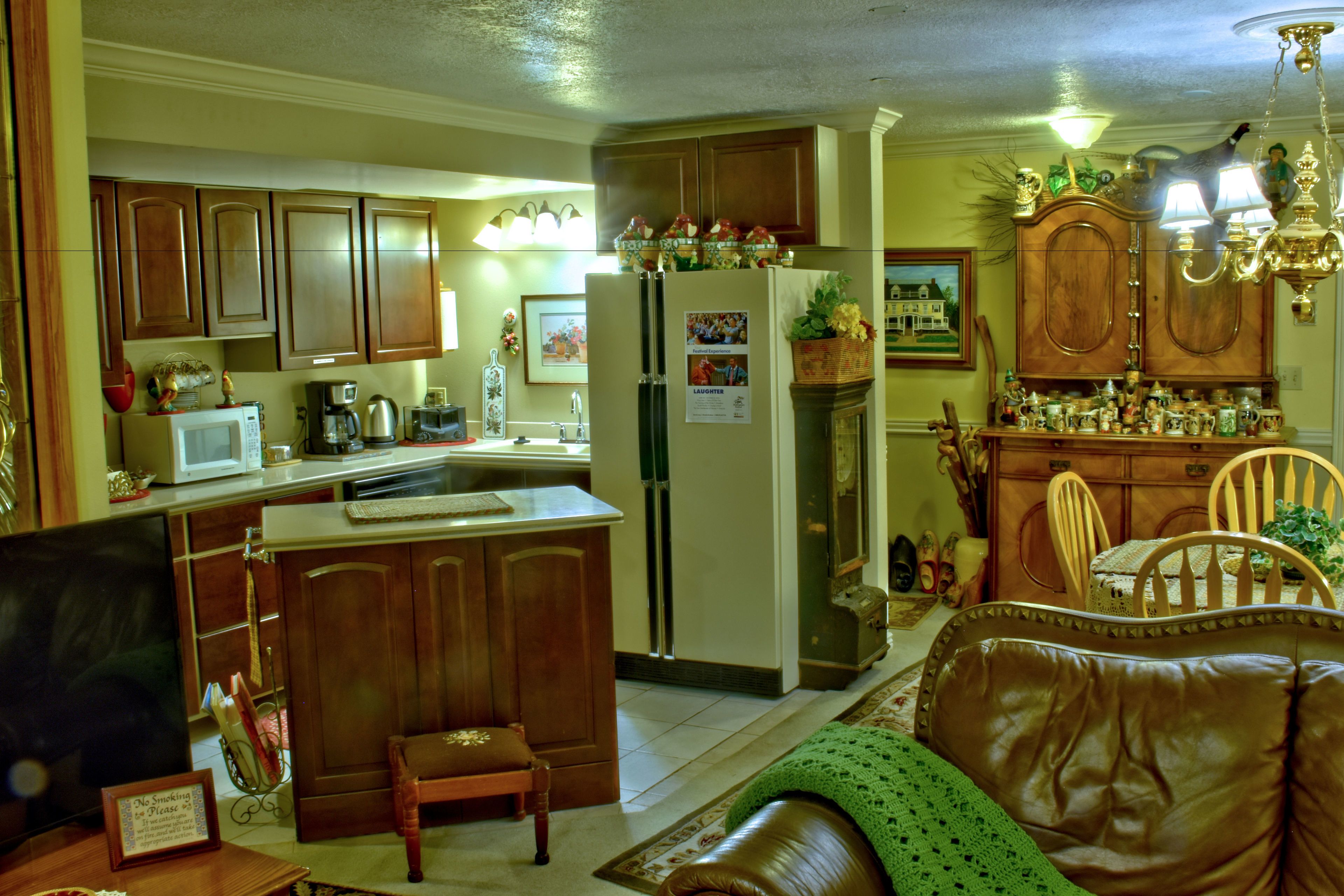 Una cocina con armarios de madera, un refrigerador y un comedor con una mesa y sillas.