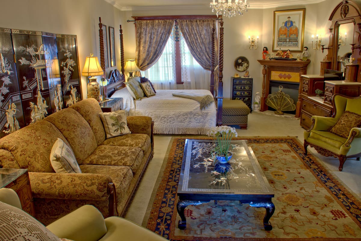 A traditional room with a bed, sofa, and a coffee table with a vase.