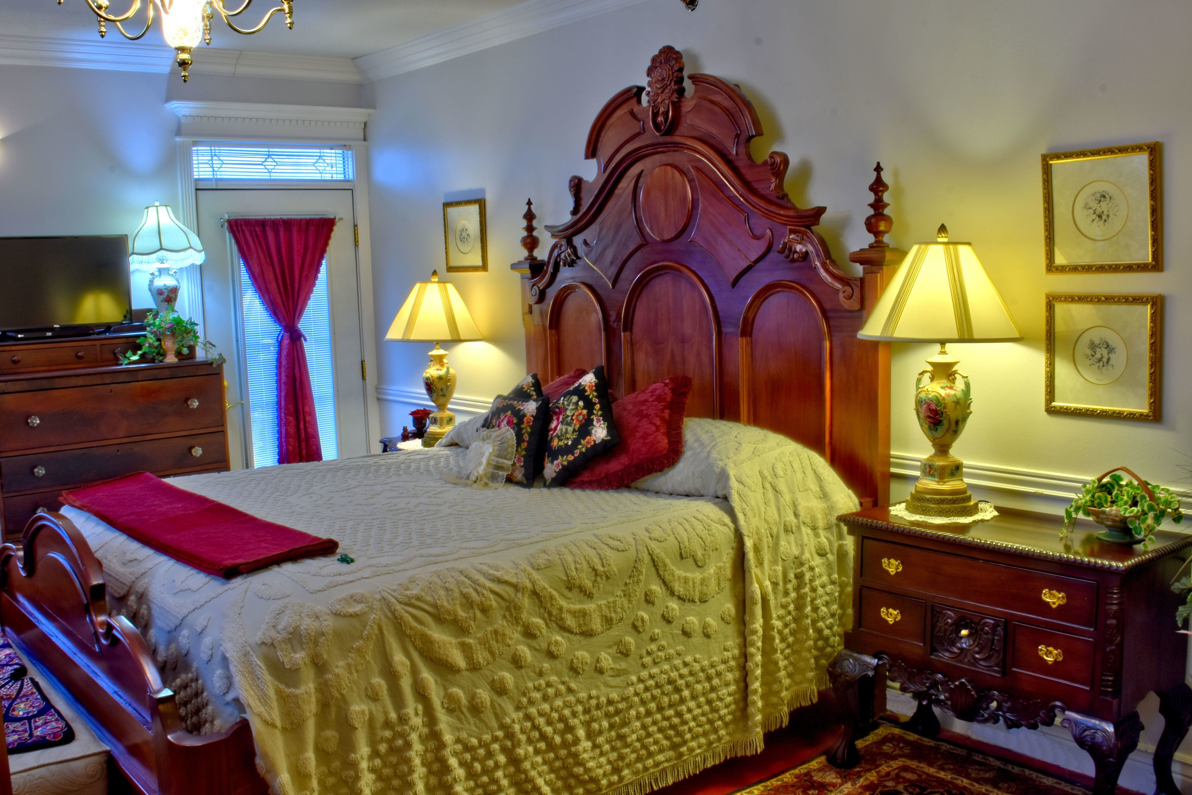 Une chambre à coucher avec un grand lit, une tête de lit en bois, des lampes de chevet, une commode et un téléviseur.