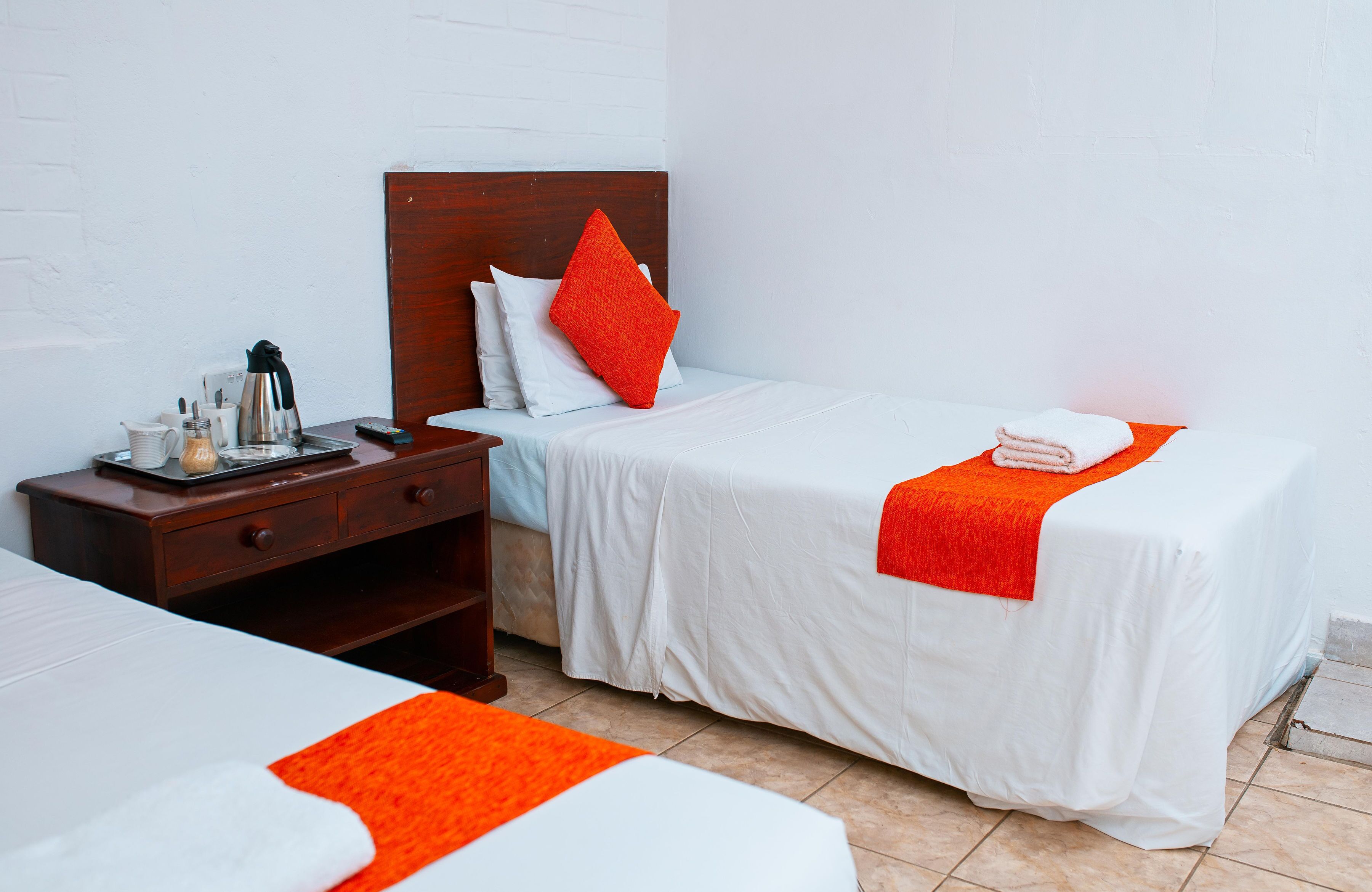 A hotel room with two beds, a wooden nightstand, and a coffee maker.