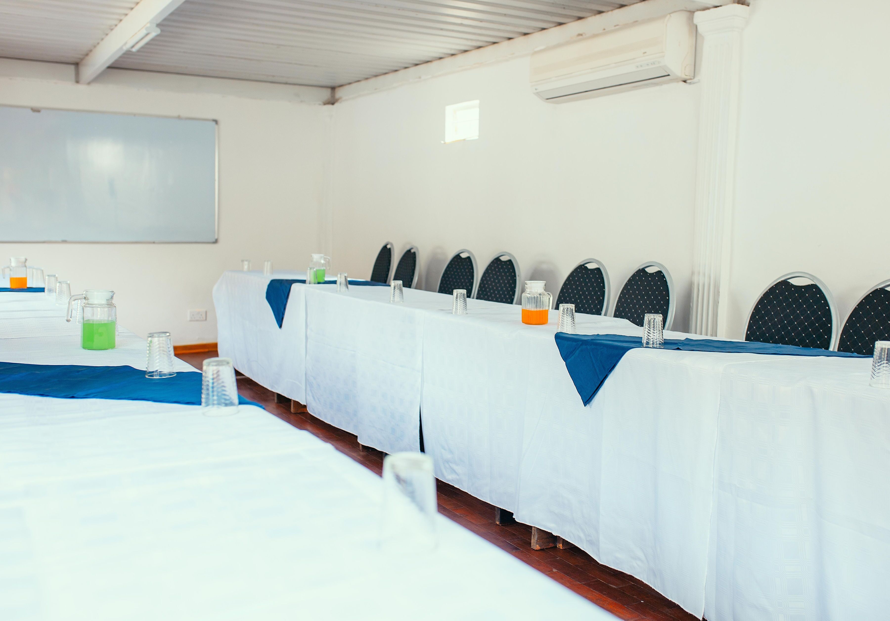 A conference room with long tables, chairs, and a whiteboard.