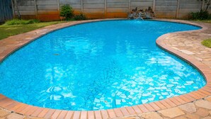 Une piscine bordée de mosaïques et dotée d’un patio en pierre.