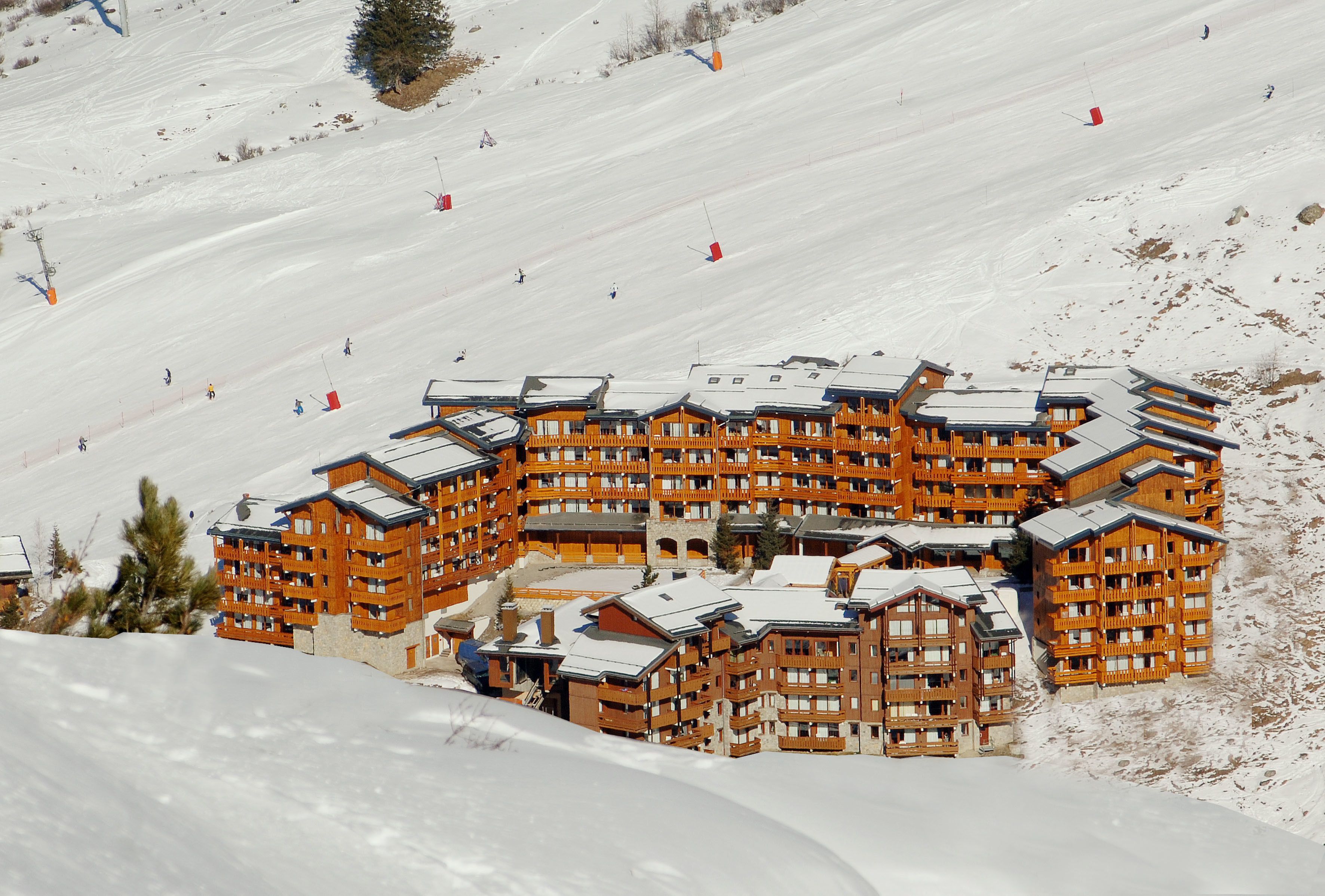 A large wooden ski resort building with multiple balconies and a ski lift in the background.