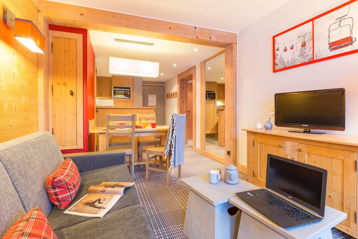Un salon confortable avec un canapé, une table basse, un ordinateur portable et un téléviseur à écran plat.