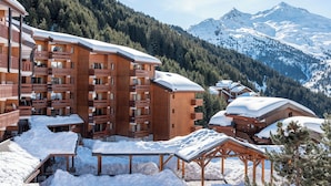 Un chalet en bois doté de plusieurs balcons et offrant une vue sur des montagnes enneigées.