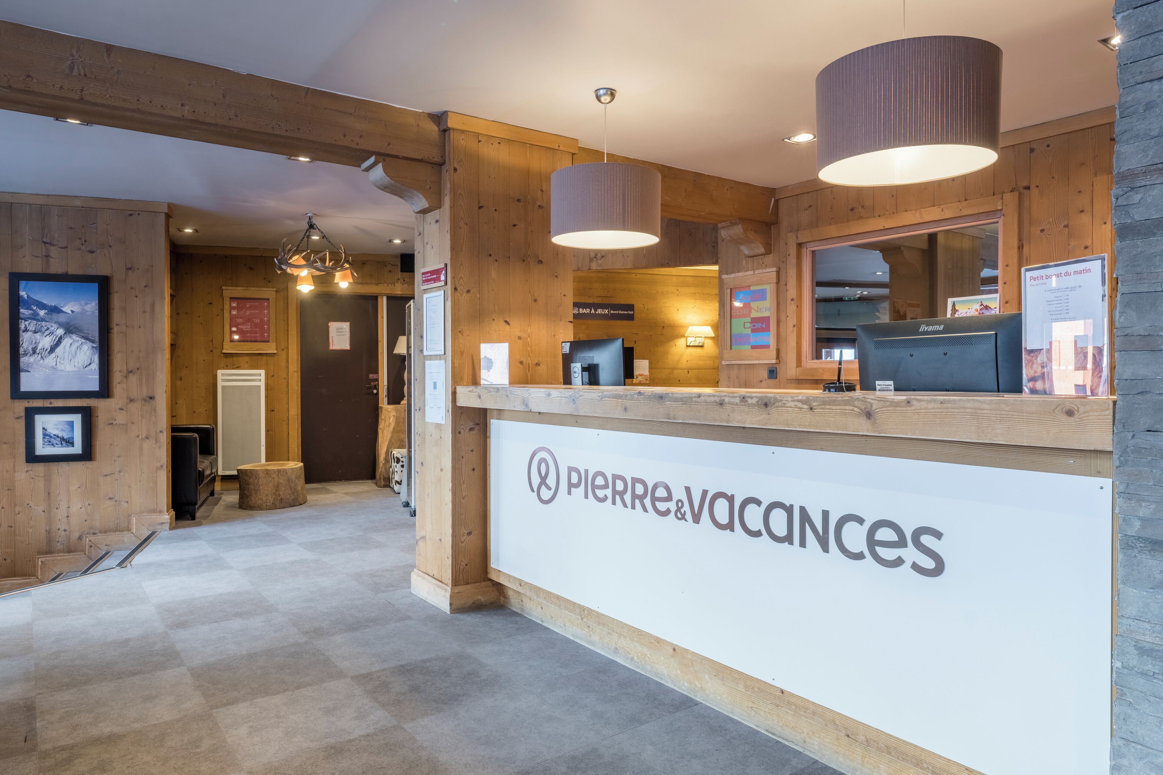 Un área de recepción con interior de madera, un mostrador de recepción y un letrero que dice Pierre & Vacances.