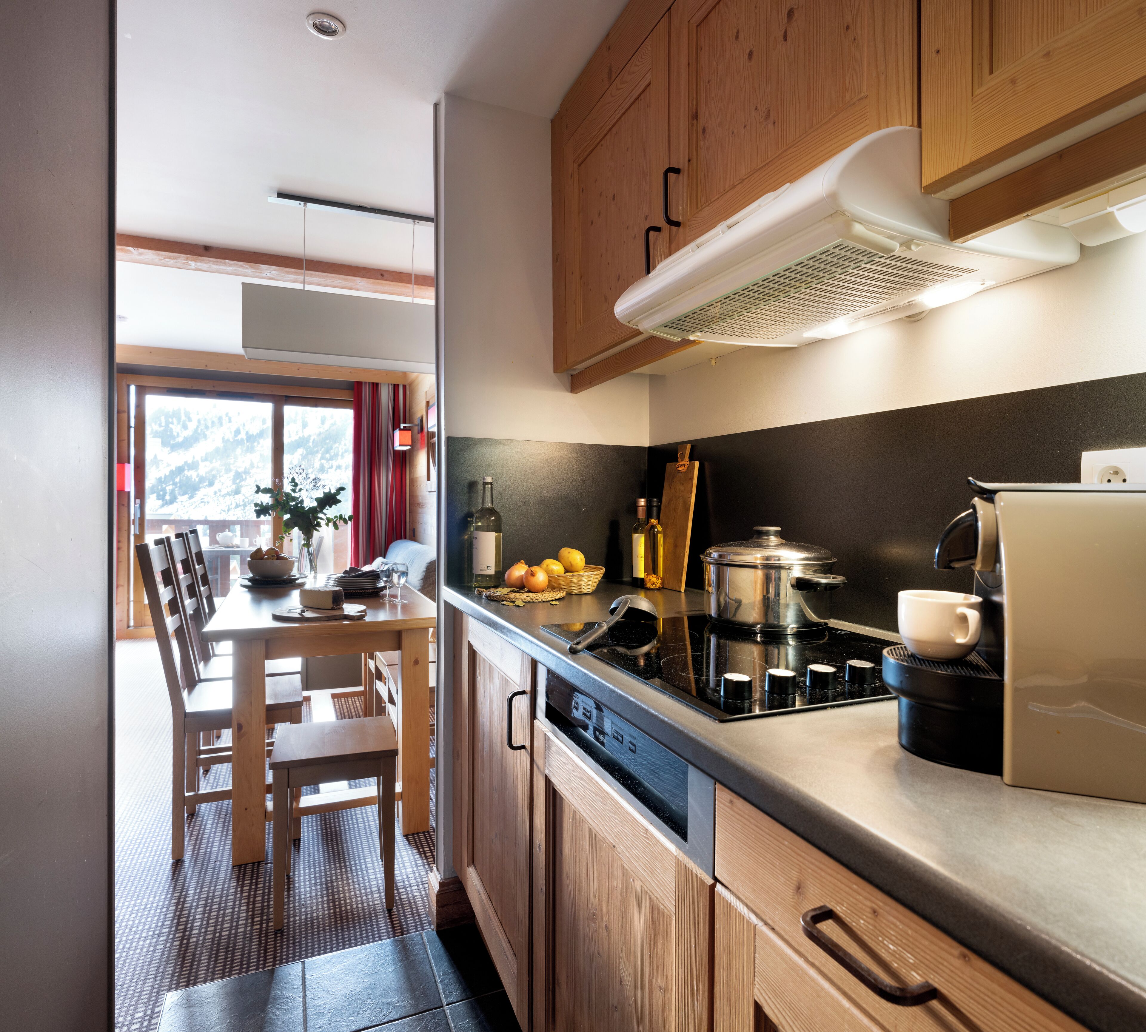Une cuisine moderne avec des meubles en bois, une cuisinière et un coin repas comprenant une table et des chaises.