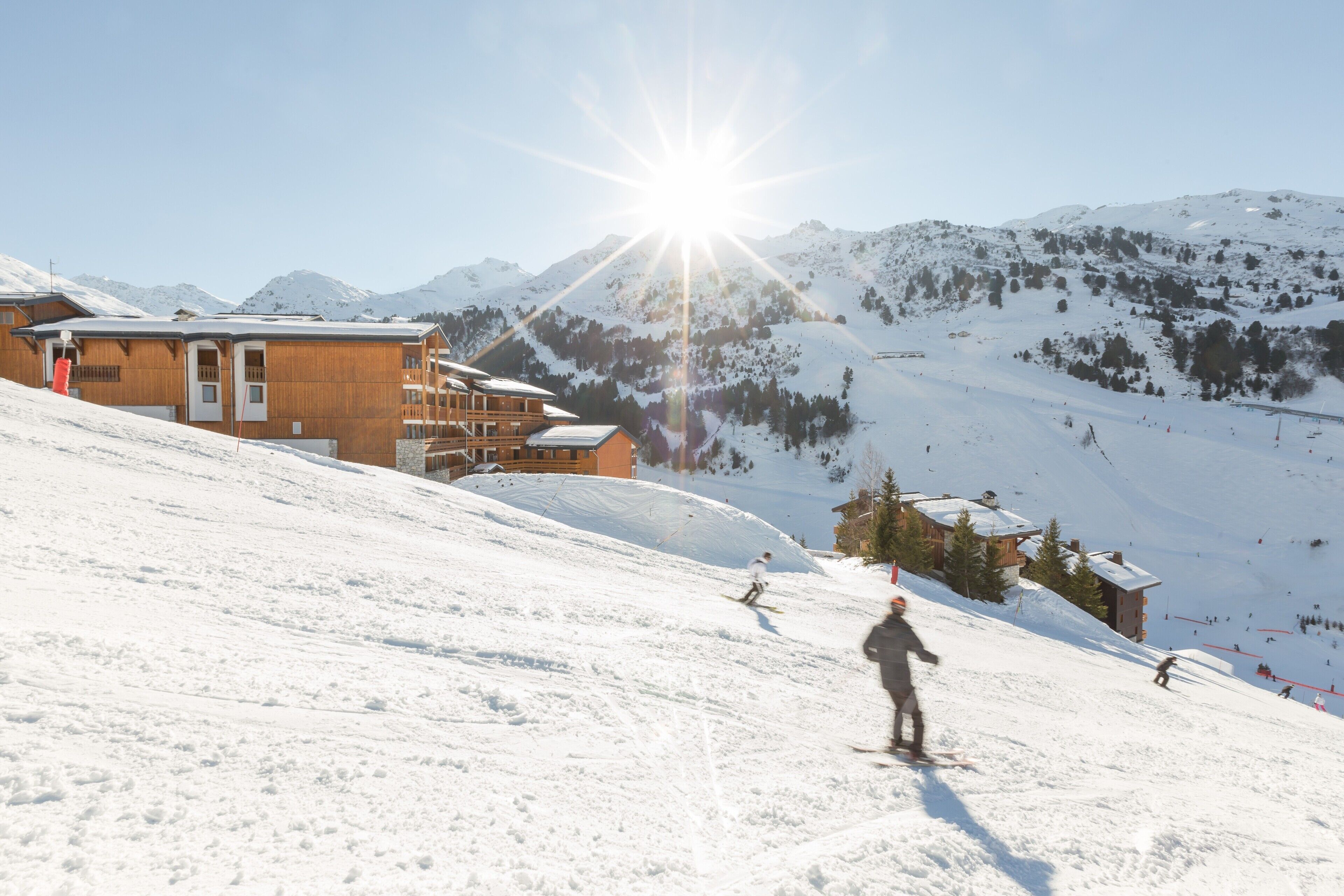 Ein Skigebiet mit einer Holzlodge, verschneiten Pisten und einem klaren Himmel.