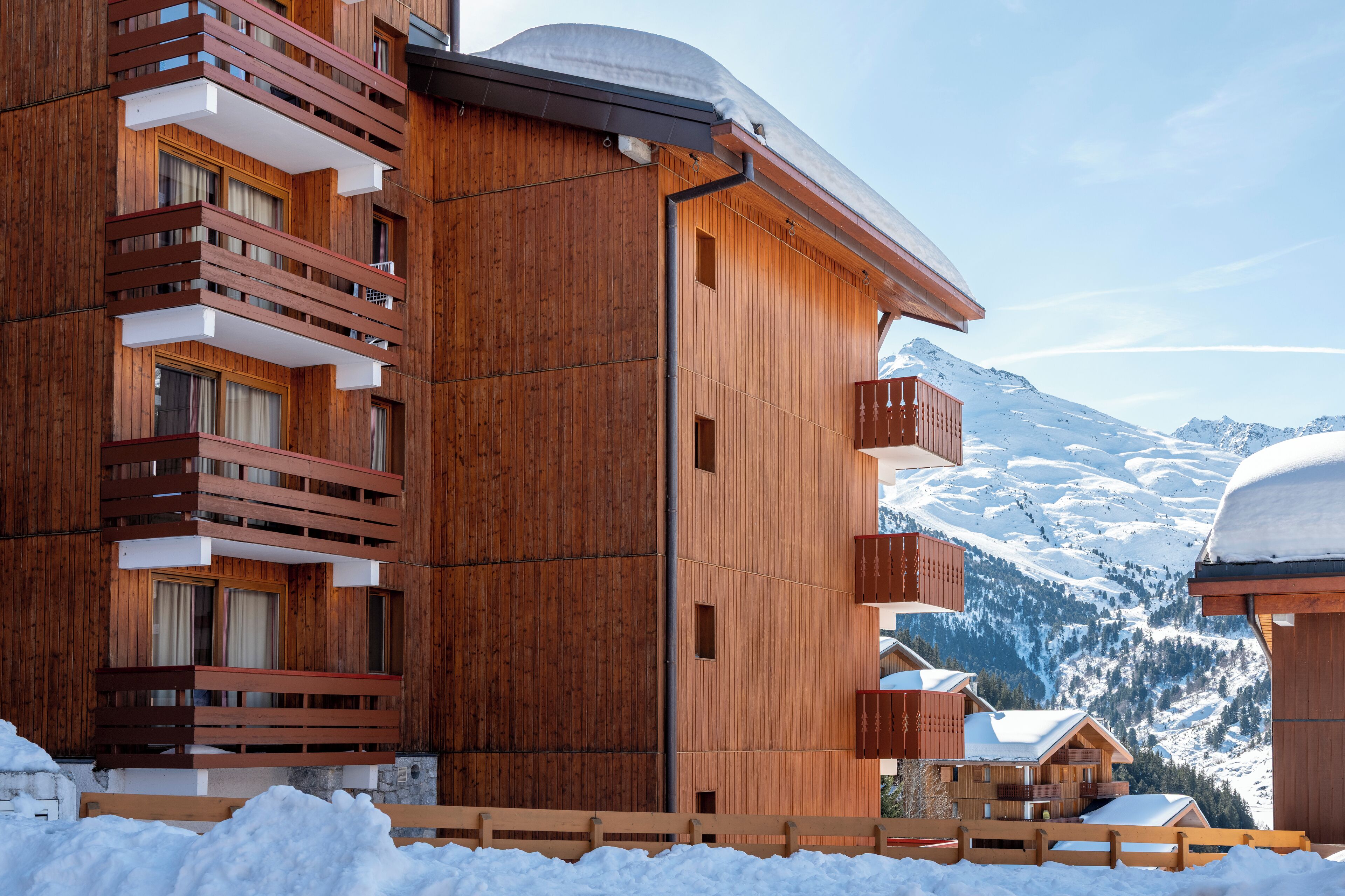 Ein Holzbalkongebäude vor verschneitem Berggelände.