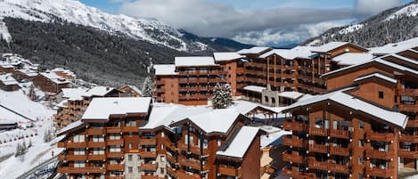 Een bergresort bedekt met sneeuw met houten gebouwen, balkons en skipistes op de achtergrond.
