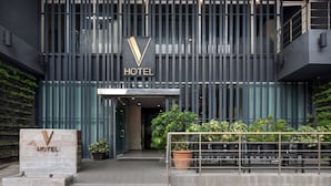 Una entrada de hotel moderna con un llamativo logotipo en forma de 'V' y letreros que indican 'HOTEL'.