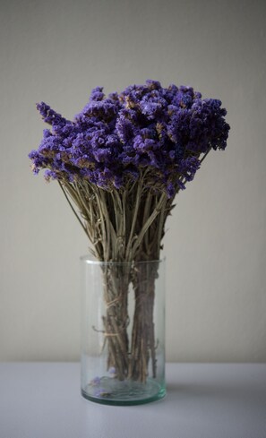 A clear glass vase containing dried purple flowers. - V Hotel (Manila)