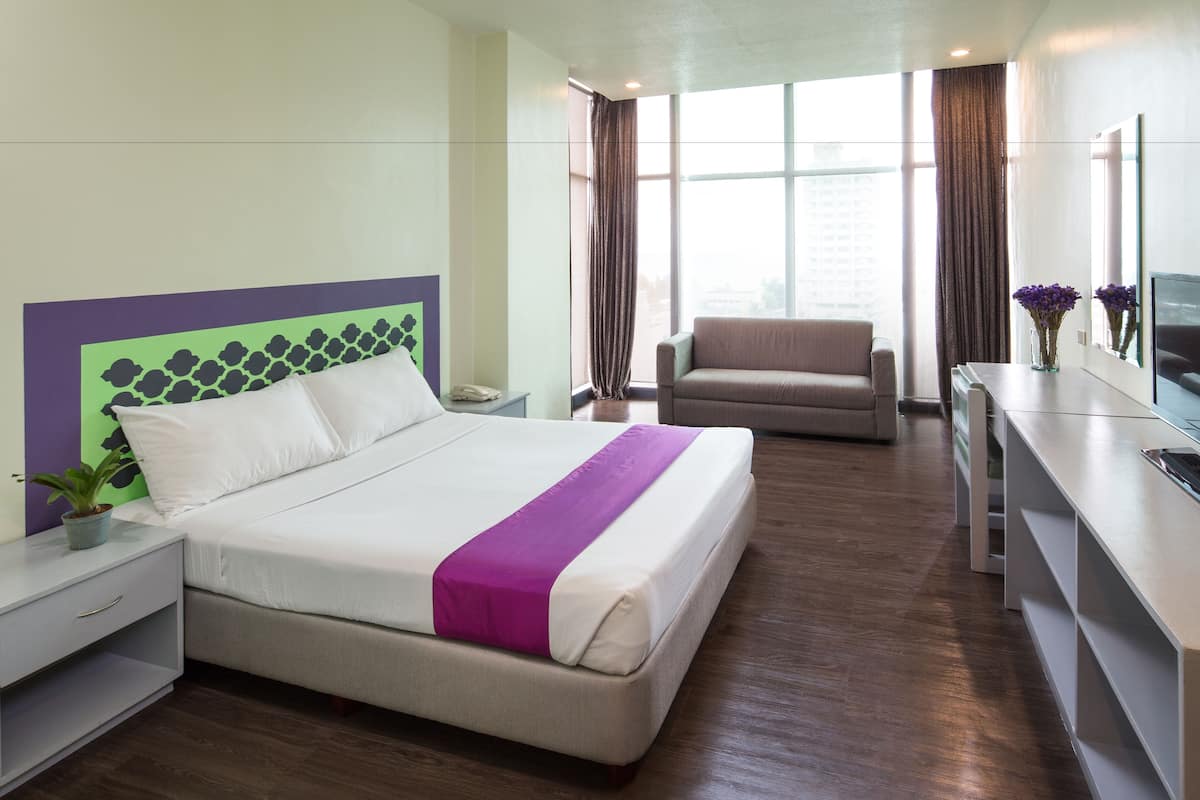 Une chambre d’hôtel moderne équipée d’un grand lit, d’un bureau, d’une chaise et d’un téléviseur.