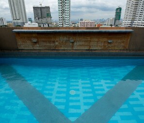 A rooftop pool with a blue tiled pattern, surrounded by a brick wall and overlooking a cityscape with high-rise buildings. - V Hotel (Manila)
