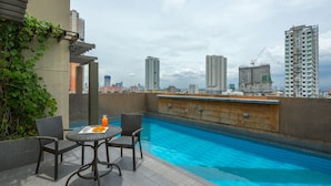 Una piscina en la azotea con vista a la ciudad, rodeada de rascacielos.