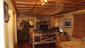 Un interior rústico con chimenea de piedra, muebles de madera y un televisor en una sala de estar acogedora.