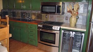 Una cocina con armarios verdes, microondas, horno y refrigerador.