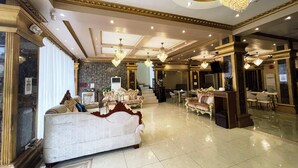 Un lobby de hotel lujoso con candelabros ornamentados, asientos cómodos y una imponente escalera.