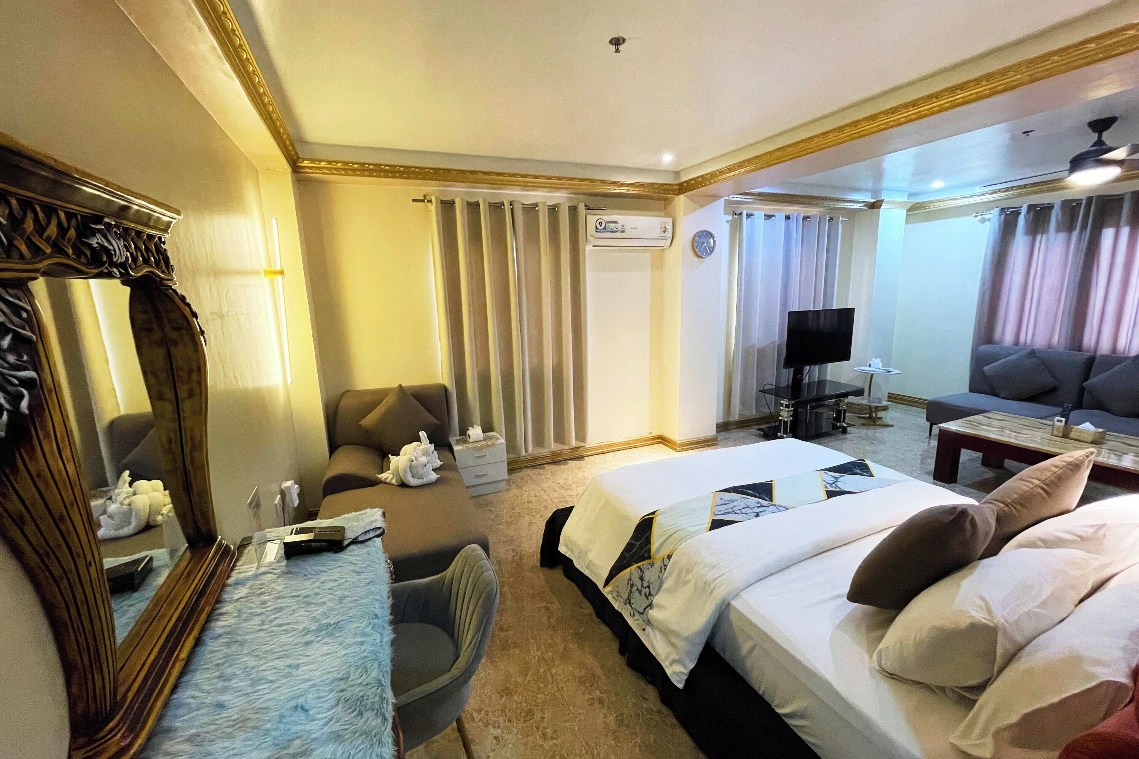 Une chambre d’hôtel avec deux lits, un bureau, une chaise, une télévision et un canapé.