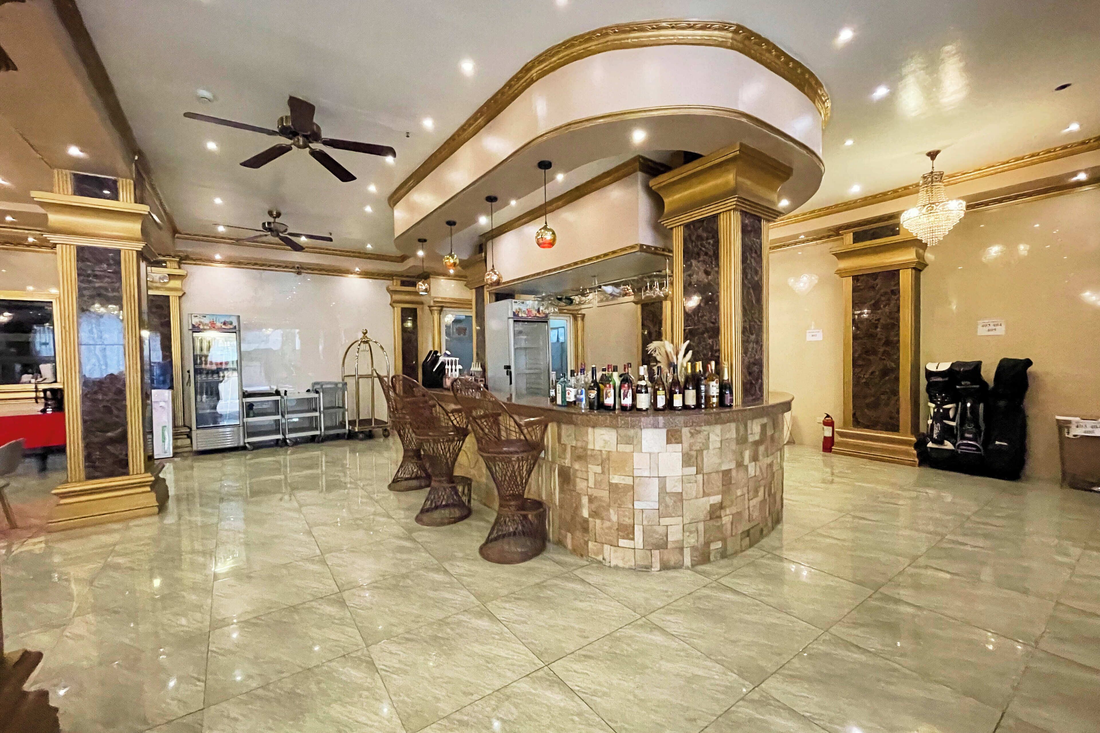 A bar area with a curved counter, multiple stools, and a ceiling fan.
