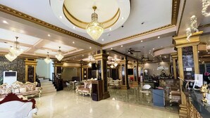 Un vestíbulo amplio con candelabros, muebles elegantes y una mesa de recepción.