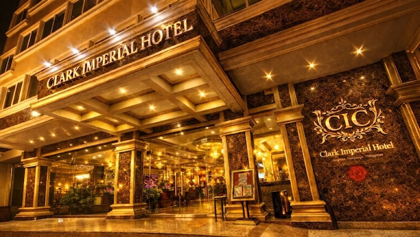 Exterior del Hotel Clark Imperial, con una entrada imponente, columnas de mármol y una fachada bien iluminada.