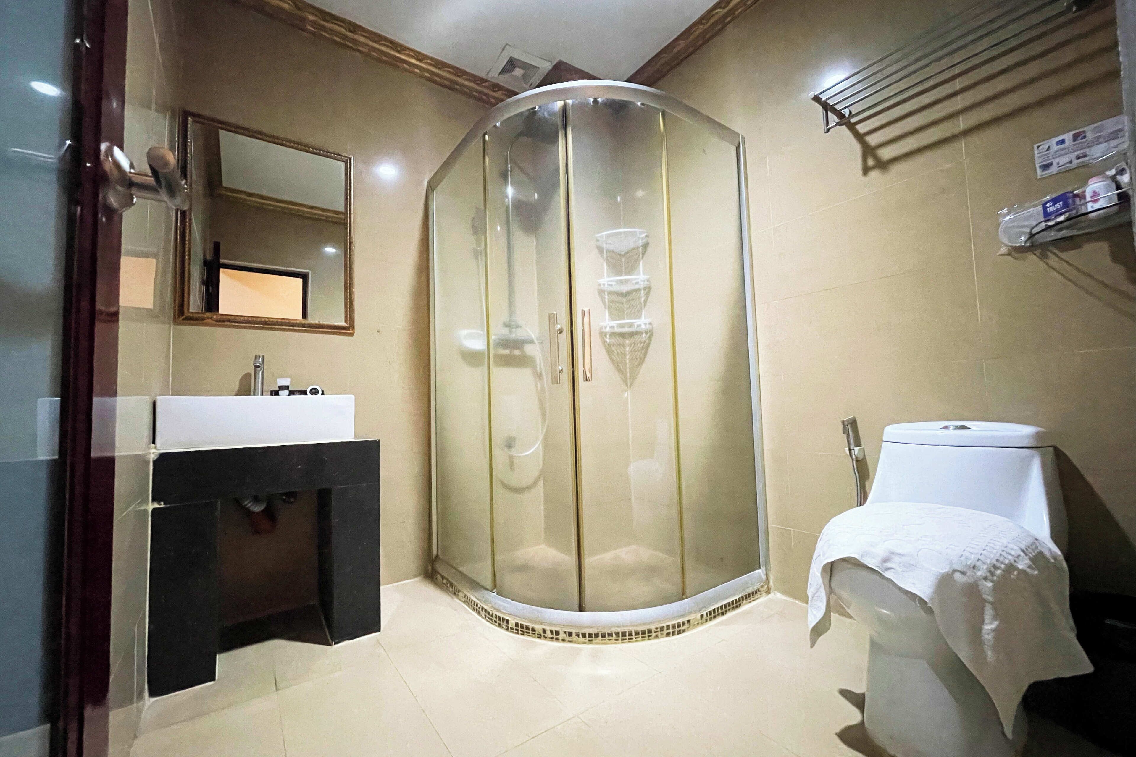A bathroom with a glass-enclosed shower, a sink, and a toilet.