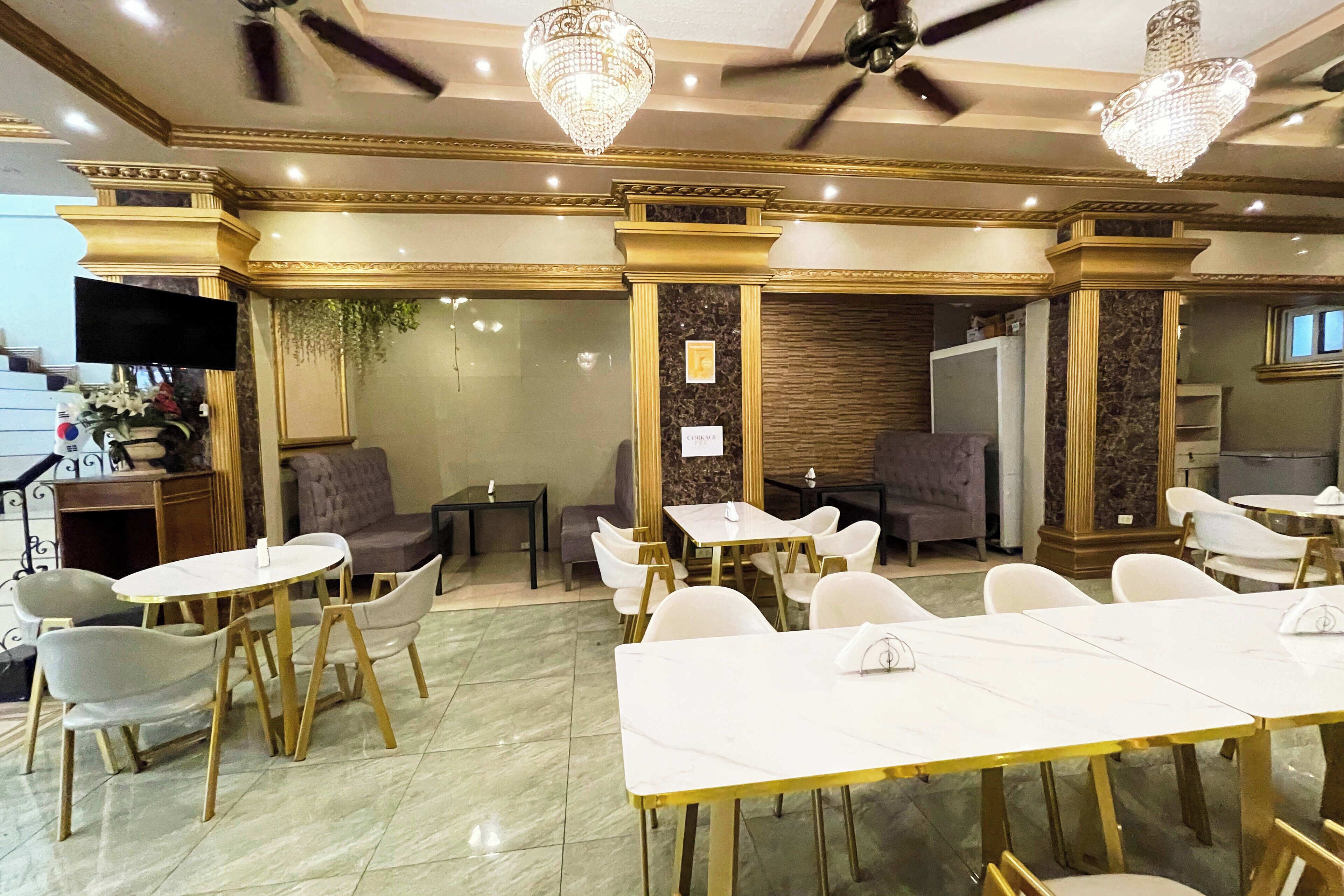 Un comedor con mesas y sillas blancas, candelabros y suelo de mármol.