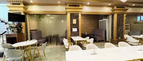 Un comedor con mesas y sillas blancas, candelabros y suelo de mármol.